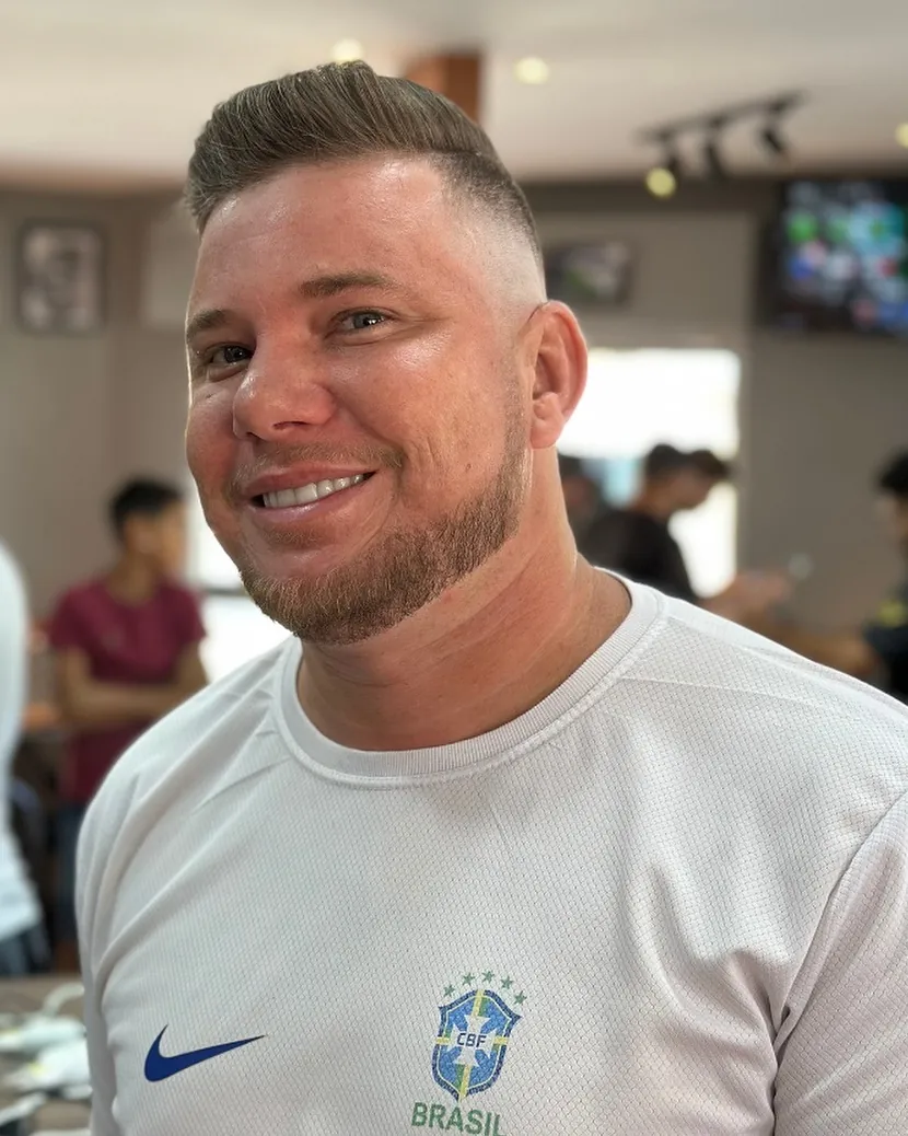 Cliente sorrindo, com corte curto e barba rente, feito na Fino Trato