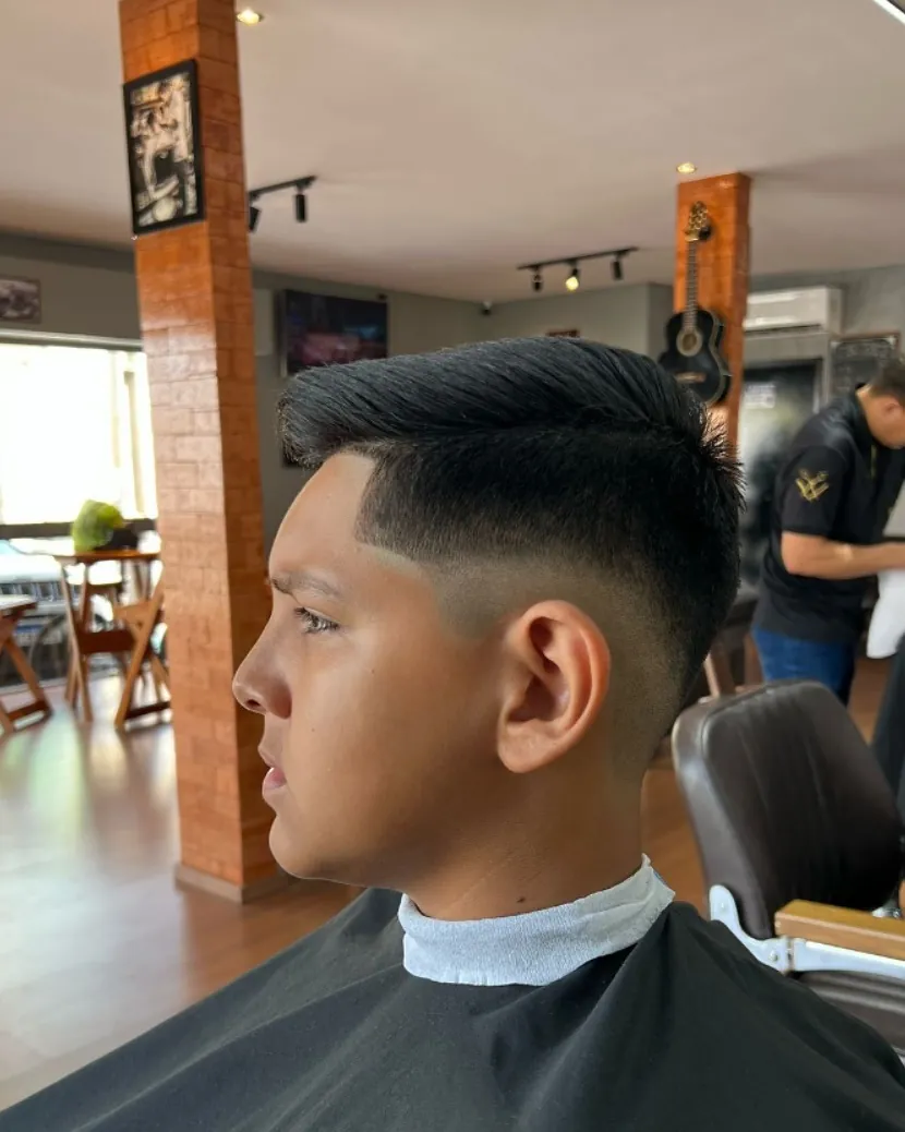 Cliente com degradê nas laterais e cabelo penteado para cima, feito na Fino Trato