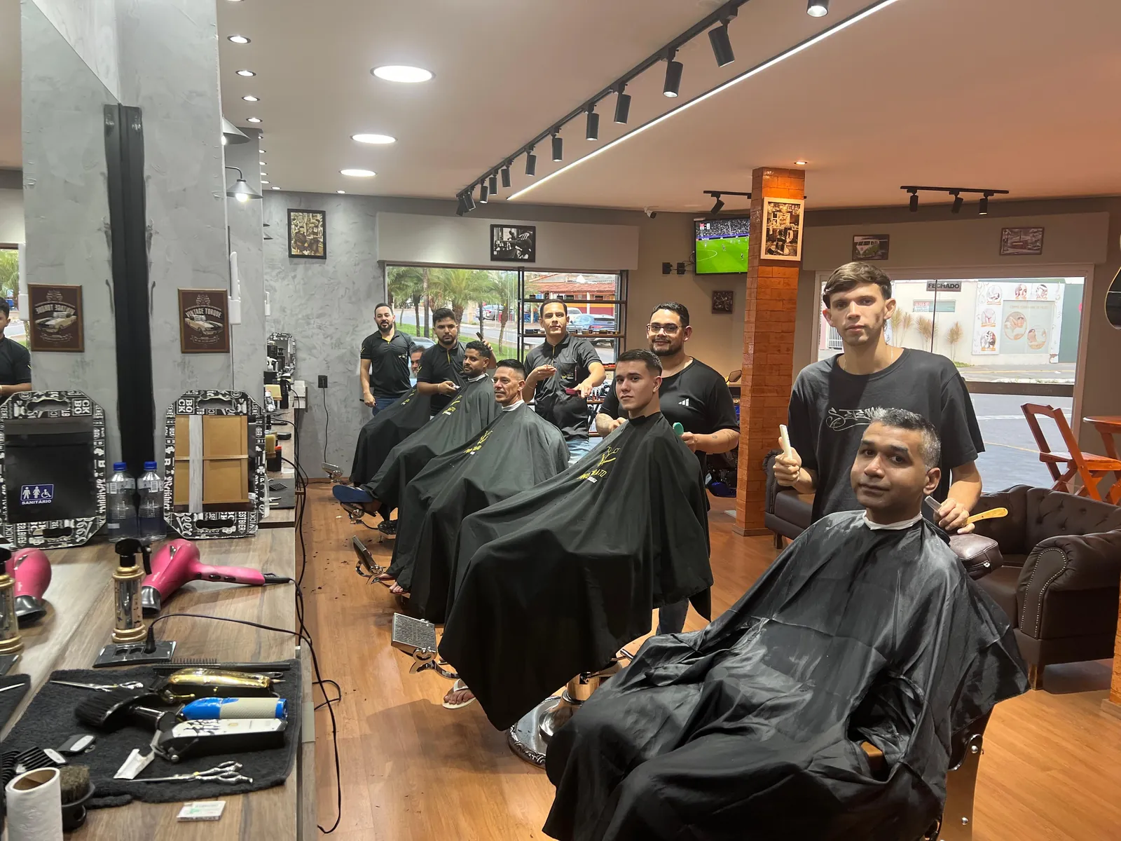 Equipe da Fino Trato reunida no salão, ao lado de clientes sentados nas cadeiras