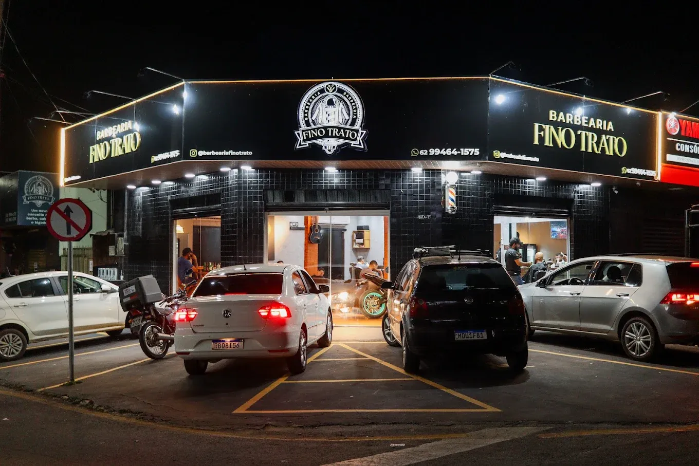 Fachada da Fino Trato Barbearia à noite, com o letreiro iluminado