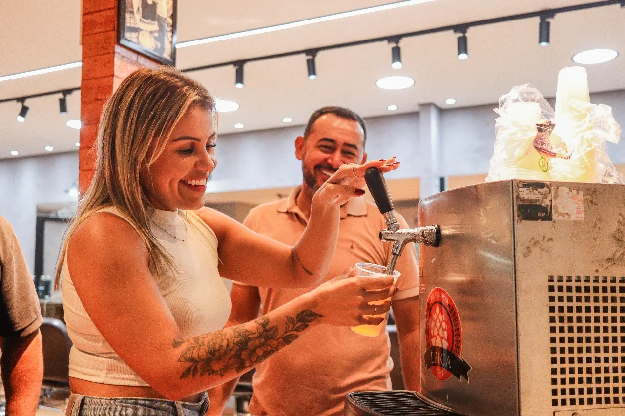 Casal servindo chope na chopeira durante a inauguração