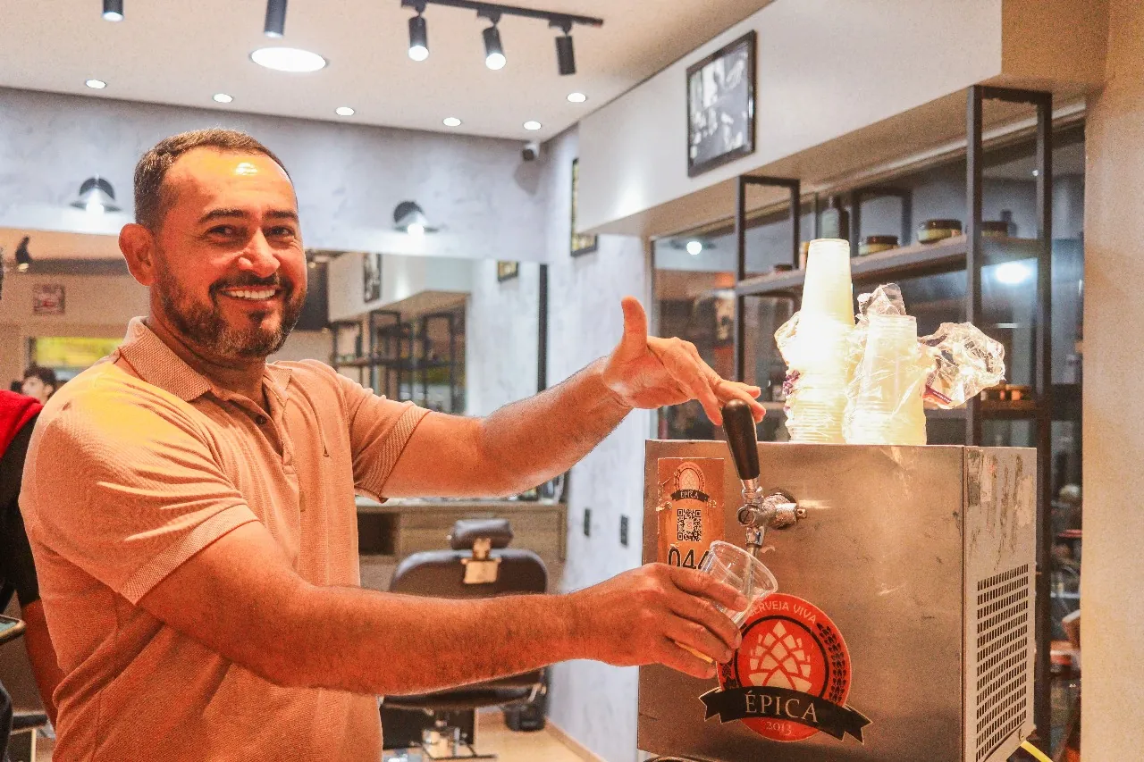 Convidado sorrindo ao lado da chopeira com um copo de chope