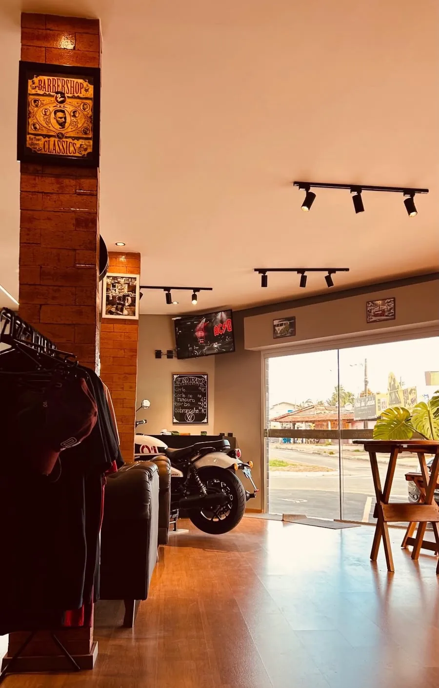 Salão da Fino Trato com uma moto em exposição, poltronas e a porta de vidro aberta para a rua